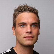 En mann med kort, stylet hår og slående blå øyne vendt mot kameraet mot en nøytral bakgrunn identifiseres som Ole Andrè Lerang.
