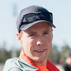 Nærbilde av en smilende Trym Rostad iført caps med teksten «team holmen» utendørs en solskinnsdag.