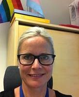 En profesjonell kvinne ved navn Stina Rydning Norstrøm, med briller og et vennlig smil, tar en selfie i kontormiljø.